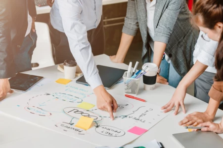 Eine Gruppe von Personen steht an einem Tisch, der mit Post-its bedeckt ist.